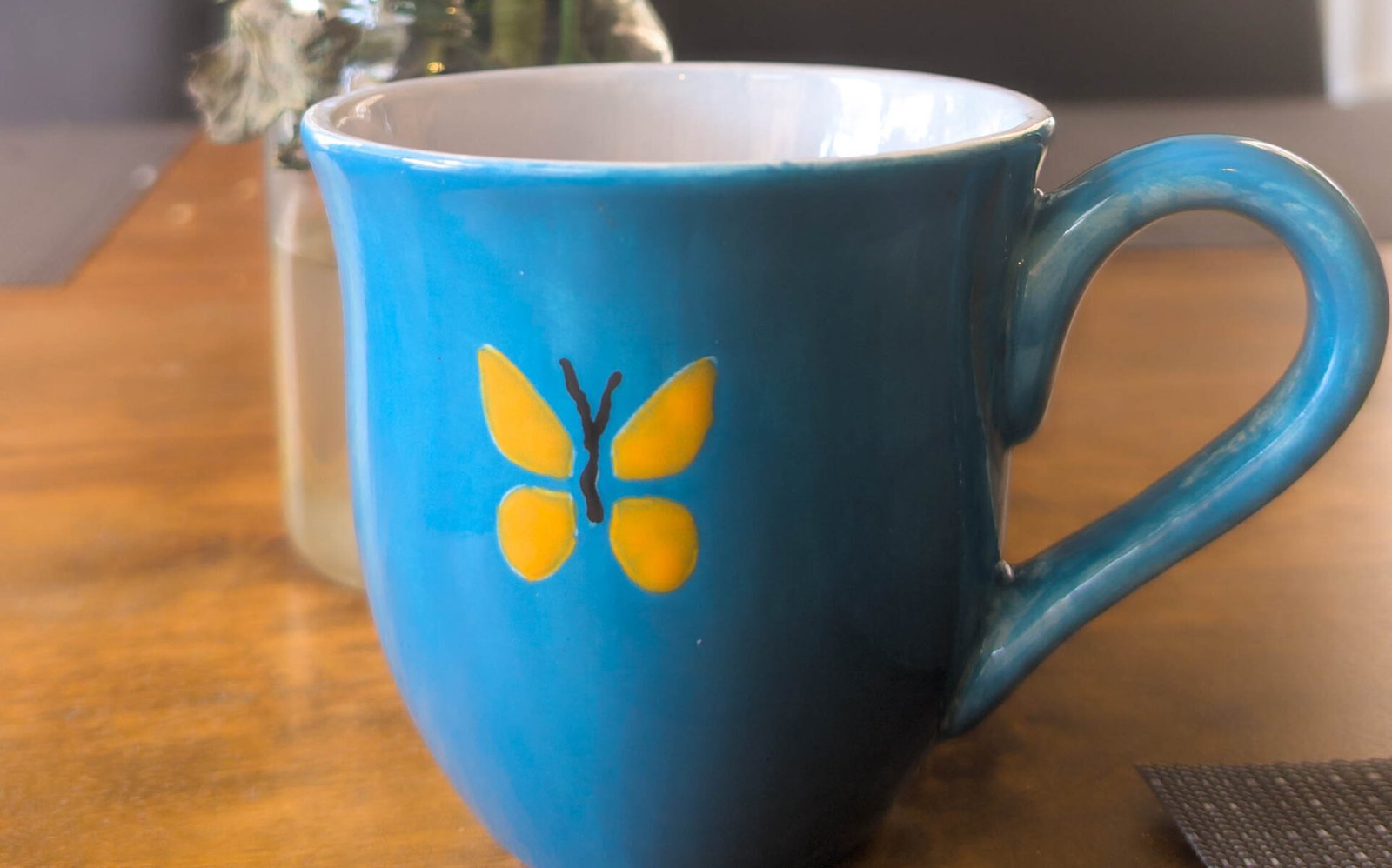 Tea cup with a butterfly in front of flowers